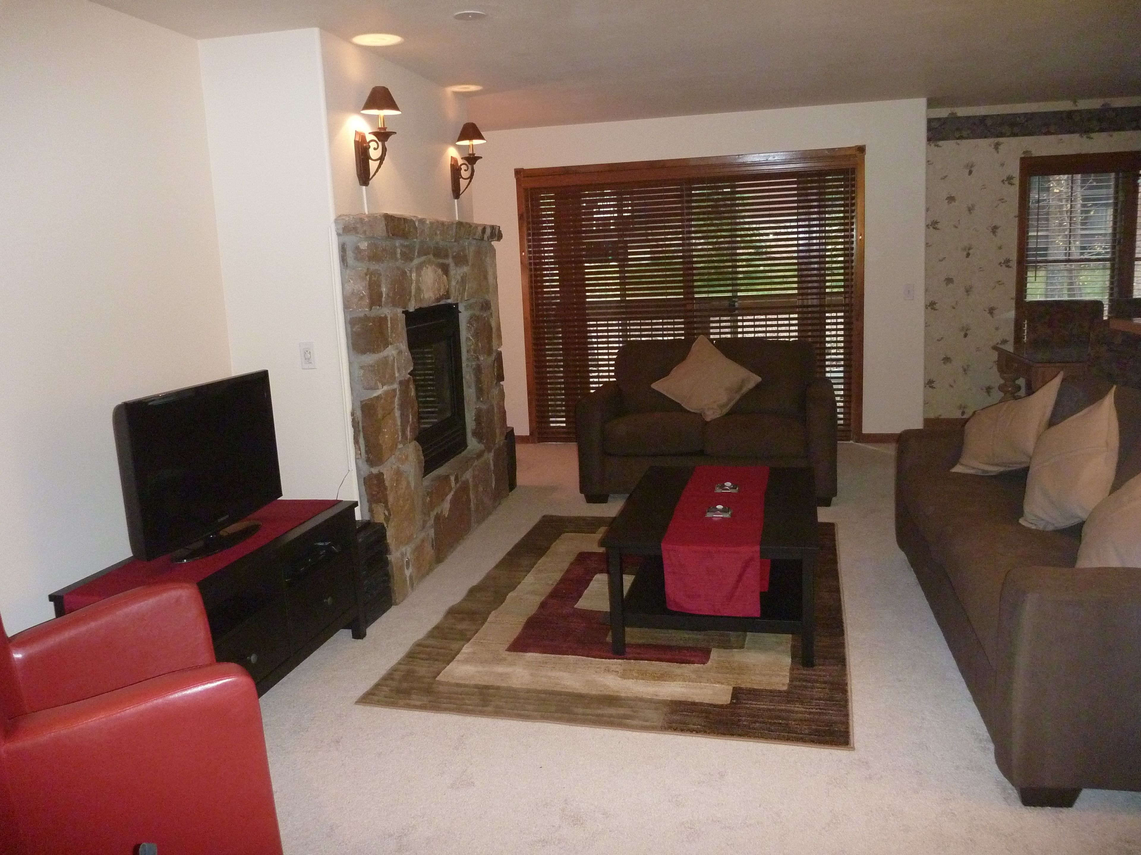 Una sala de estar con chimenea de piedra, televisor, sofá y mesa de centro.