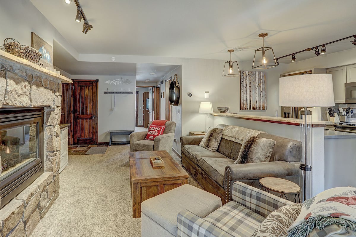 A cozy living room with a fireplace, a sofa, a coffee table, and a dining area.