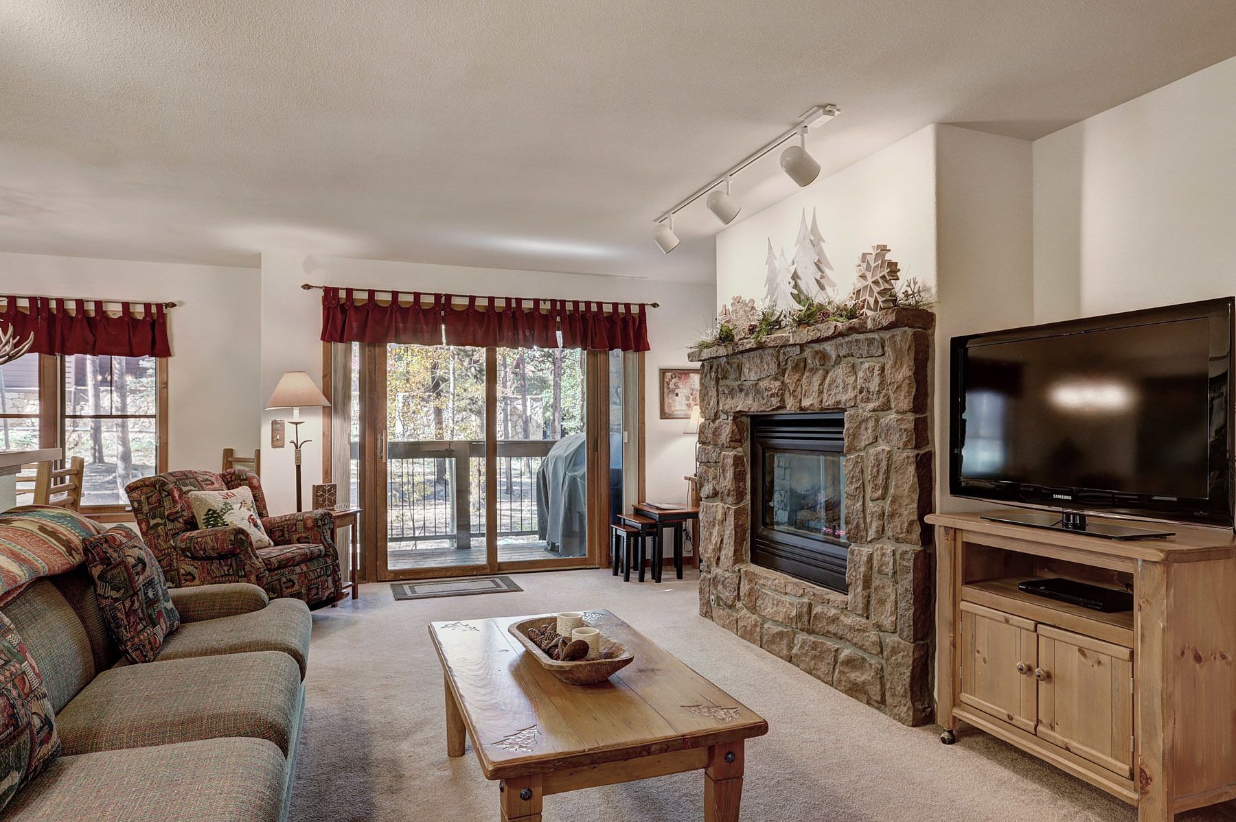 A cozy living room with a stone fireplace, a television, a sofa, and a coffee table.