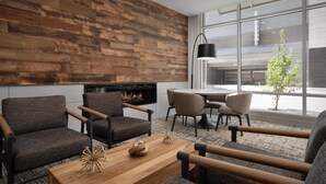 A modern living room with a fireplace, comfortable seating, and large windows offering a view of the outdoors. - Hilton Garden Inn Denver Downtown (Denver)