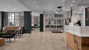 A modern hotel lobby with a reception desk, seating area, and large windows. - Hilton Garden Inn Denver Downtown (Denver)