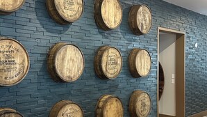 A wall with multiple wooden barrels arranged in a grid pattern against a blue brick wall. - Hilton Garden Inn Denver Downtown (Denver)