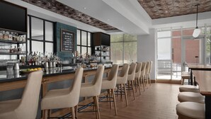 A bar area with a long counter, multiple stools, and a variety of bottles and glasses. - Hilton Garden Inn Denver Downtown (Denver)