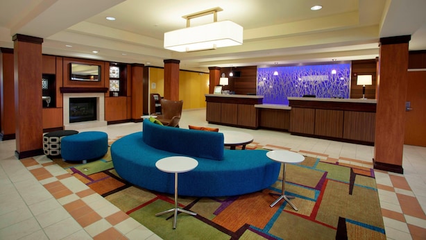 Un moderno vestíbulo de hotel con un sofá azul, una chimenea, un mostrador de recepción y una zona de bar.