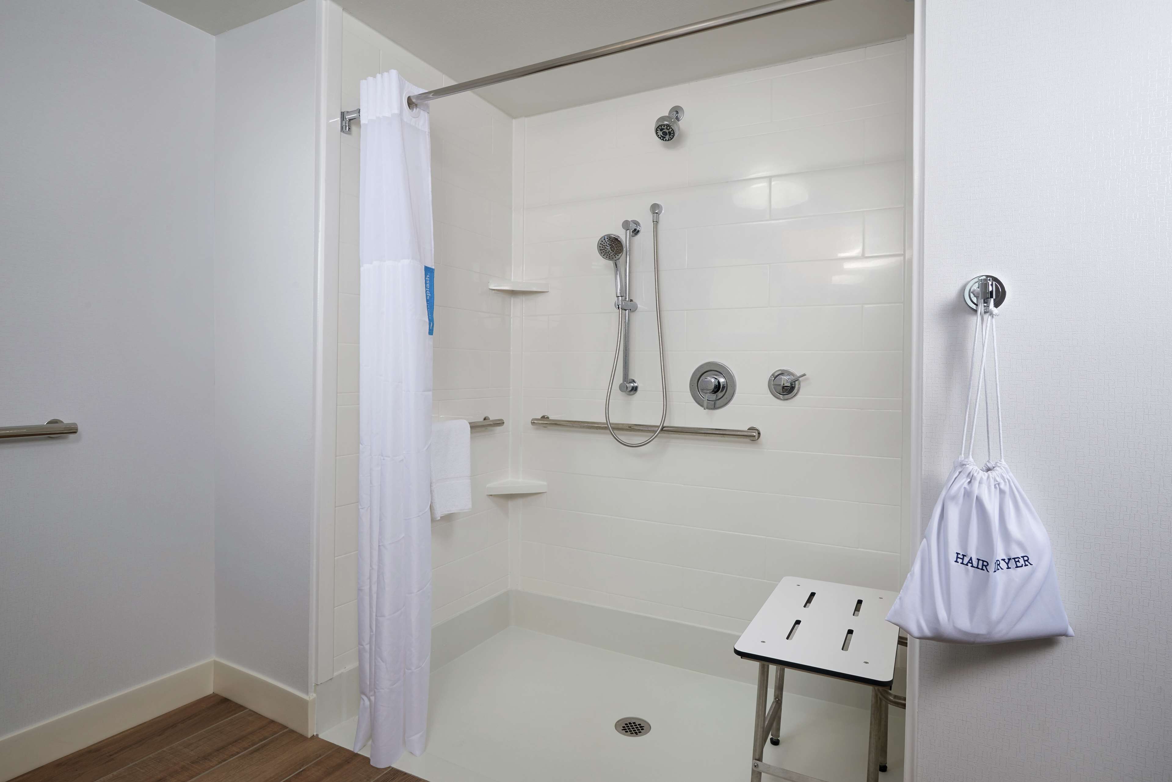 Un baño moderno con cabina de ducha, lavamanos blanco y perchero.