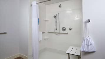 Un baño moderno con cabina de ducha, lavamanos blanco y perchero.