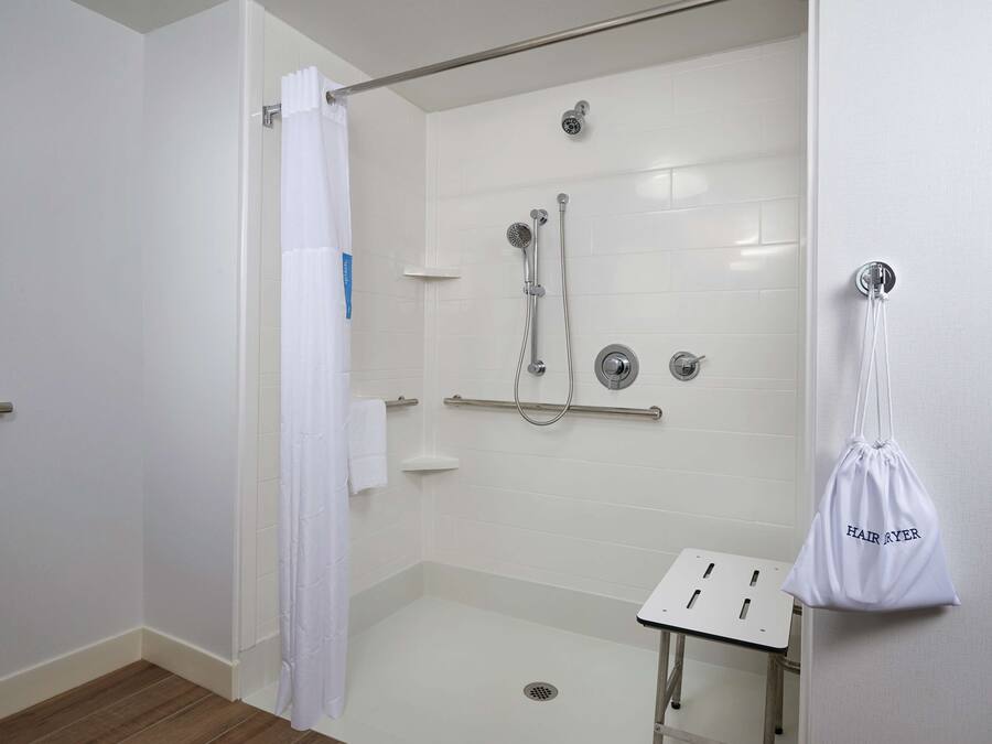 Un baño moderno con cabina de ducha, lavamanos blanco y perchero.