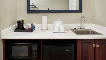 A kitchenette with a microwave, dishwasher, coffee maker, and a sink.