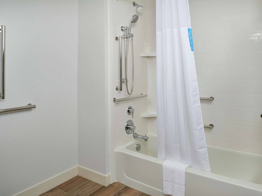 A bathroom with a bathtub, a shower, and a handrail.