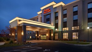 A modern hotel entrance with a prominent sign, covered walkway, and a parking lot with handicapped accessibility. - Hampton Inn & Suites Rogers (Rogers)