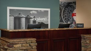 A reception desk with a framed picture of silos, a laptop, and a Hilton Honors sign. - Hampton Inn & Suites Rogers (Rogers)