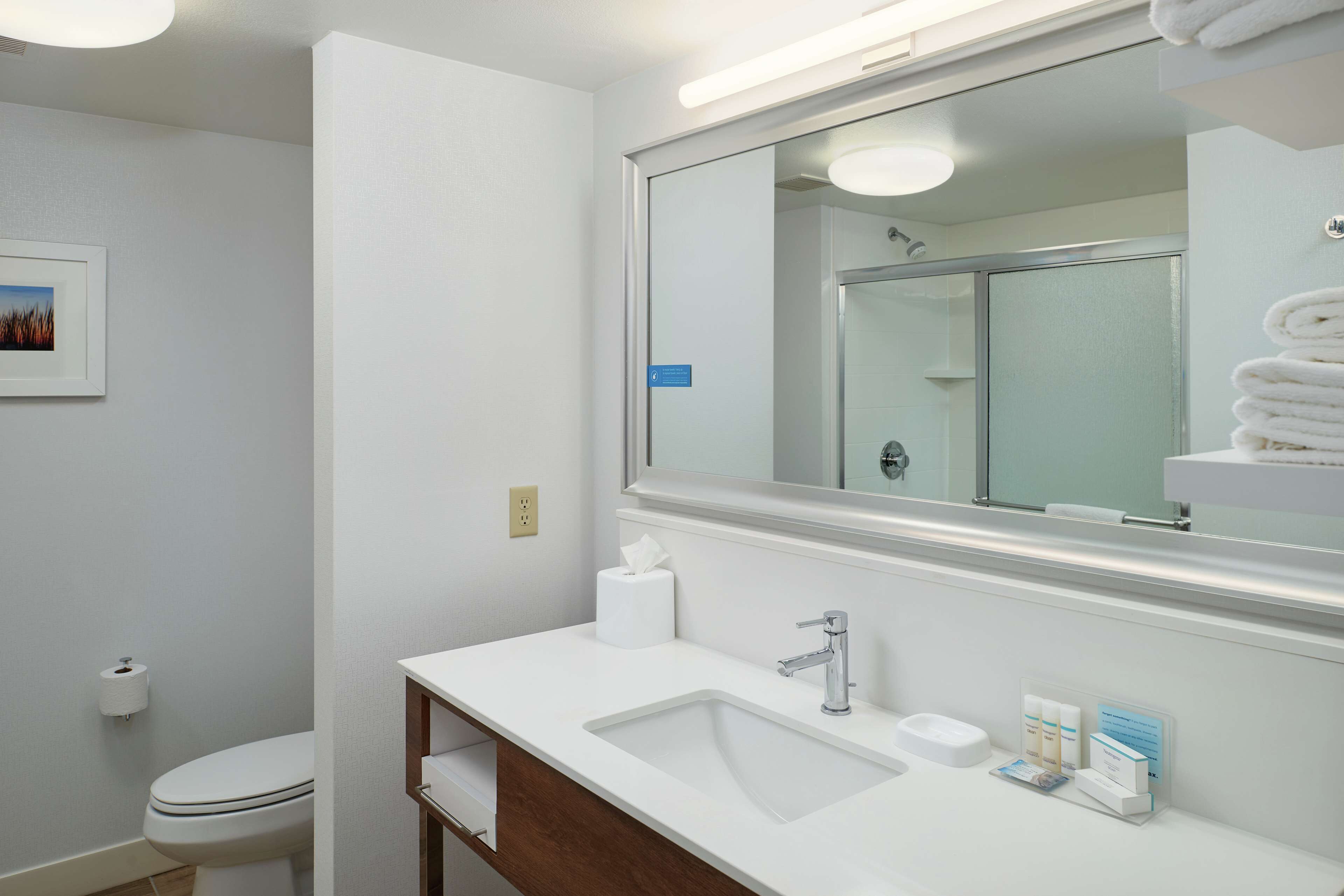 Une salle de bain moderne avec un lavabo blanc, un miroir et des toilettes.
