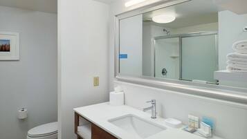 Une salle de bain moderne avec un lavabo blanc, un miroir et des toilettes.