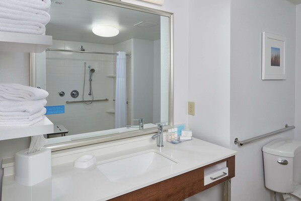Un baño con un espejo grande, lavabo blanco y cabina de ducha de cristal.