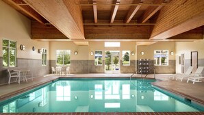 An indoor swimming pool with a wooden ceiling, tiled walls, and windows. - Hampton Inn & Suites Rogers (Rogers)