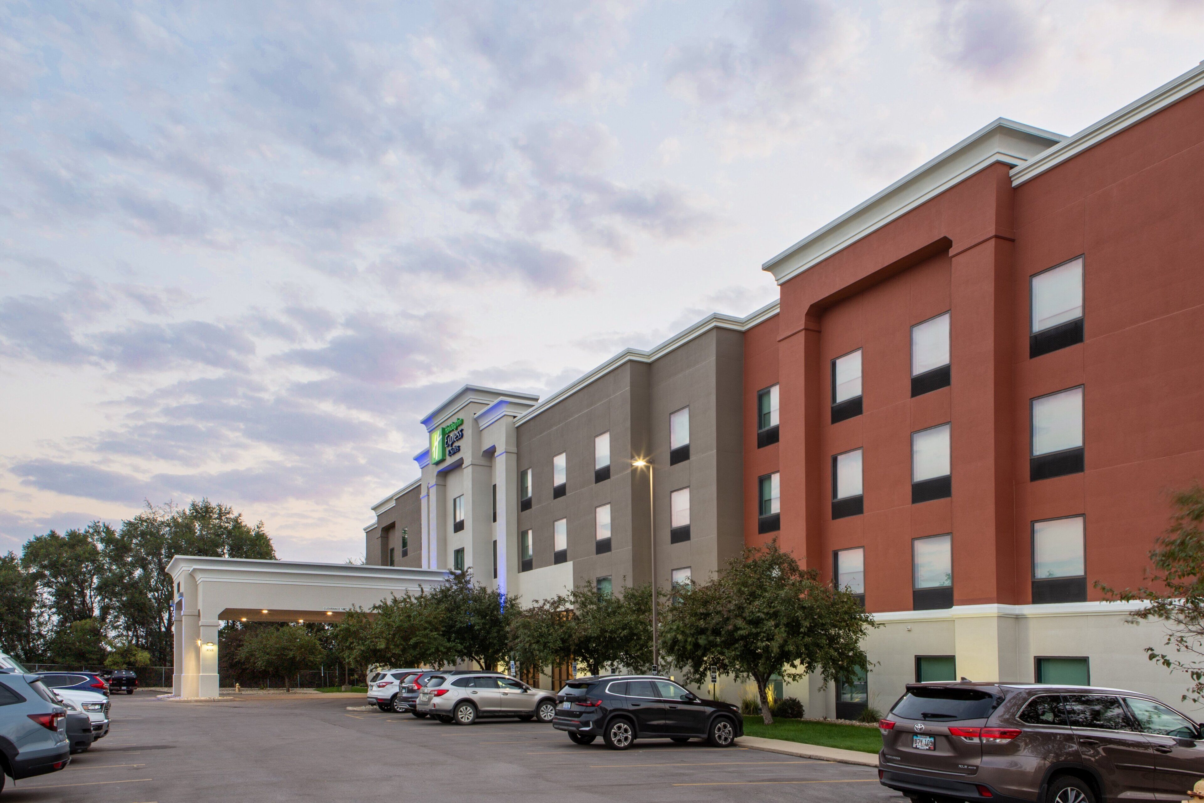 A hotel with multiple floors, a parking lot, and a covered entrance.