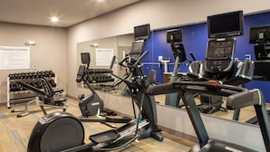 Un centre de remise en forme équipé de tapis de course, de vélos elliptiques et d’haltères.