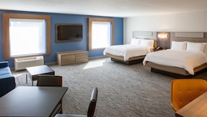 Une chambre d’hôtel avec deux lits, un bureau, une chaise, une télévision et une fenêtre.