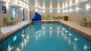 Une grande piscine intérieure dotée de nombreuses chaises longues et recouverte d’une bâche bleue sur le côté gauche.
