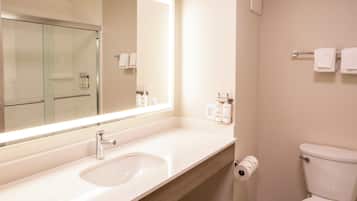 A bathroom with a large mirror, a sink, a toilet, and a towel rack.