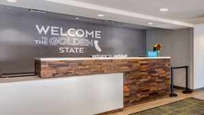 A reception desk with a "Welcome to the Golden State" sign, a Hilton logo, and a wooden wall design. - Hampton Inn Carlsbad-North San Diego County (Carlsbad)
