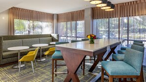 A modern hotel lobby with a large seating area, a central table, and large windows with curtains. - Hampton Inn Carlsbad-North San Diego County (Carlsbad)