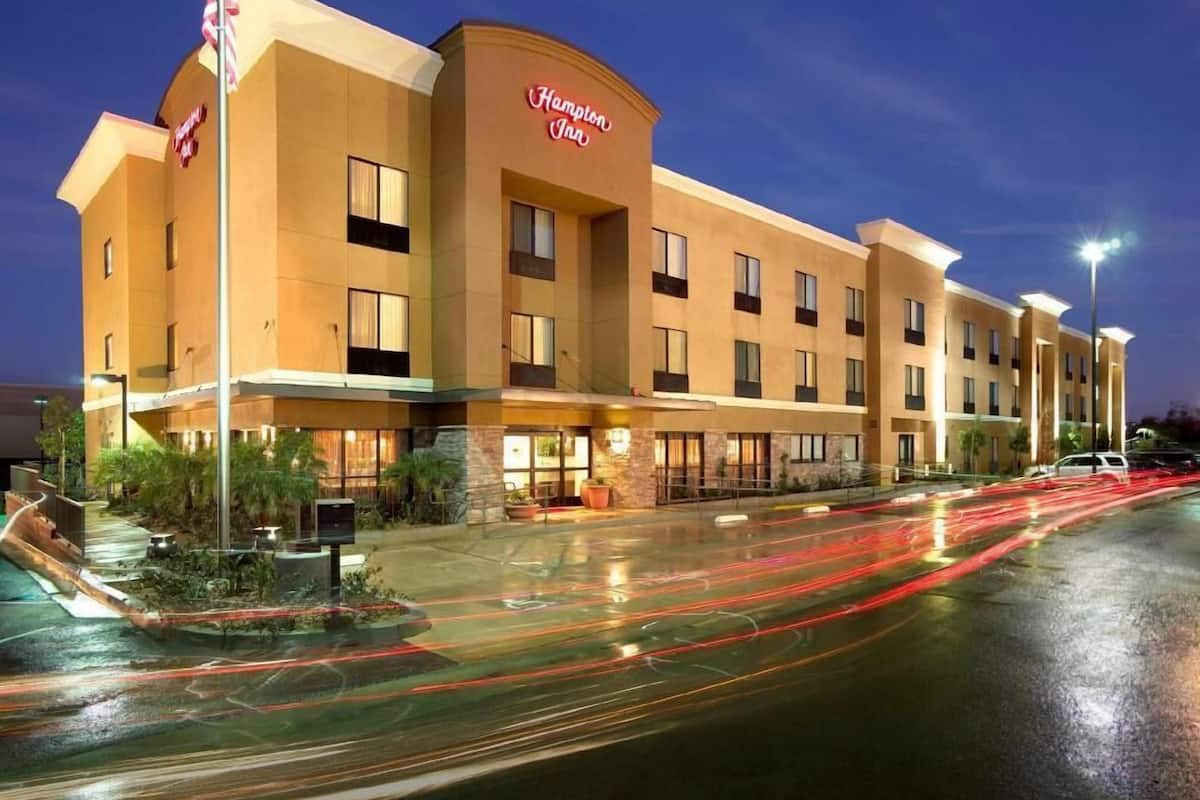A Hampton Inn hotel with a flat roof, multiple windows, and a sign on the building.