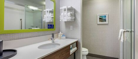 A modern bathroom with a large mirror, a sink, a toilet, and a shower area.