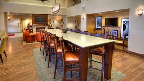 A spacious dining area with a long table, multiple chairs, and a television mounted on the wall.