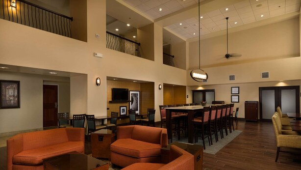 A spacious lobby with a high ceiling, multiple seating areas, and a dining setup.