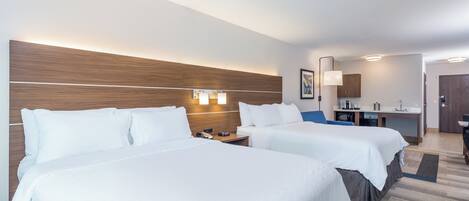 Habitación de hotel con dos camas, un escritorio, una silla, un microondas y una puerta.
