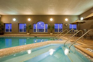 An indoor swimming pool with clear blue water, tiled steps, and a clock on the wall. - Holiday Inn Express & Suites Eau Claire North by IHG (Chippewa Falls)