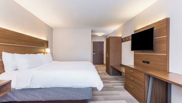 A hotel room with a bed, a TV, a wardrobe, and a desk.