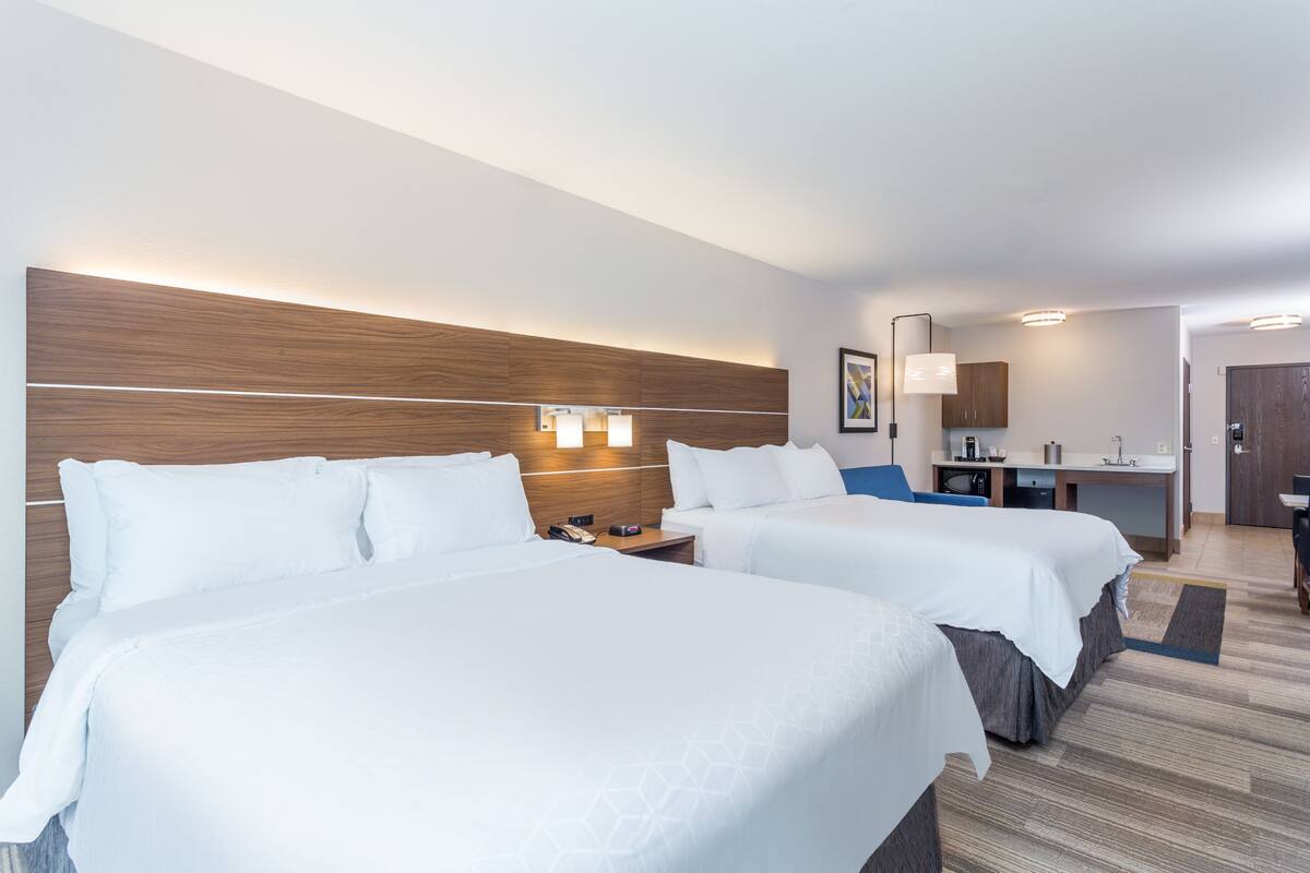 Habitación de hotel con dos camas, un escritorio y baño.