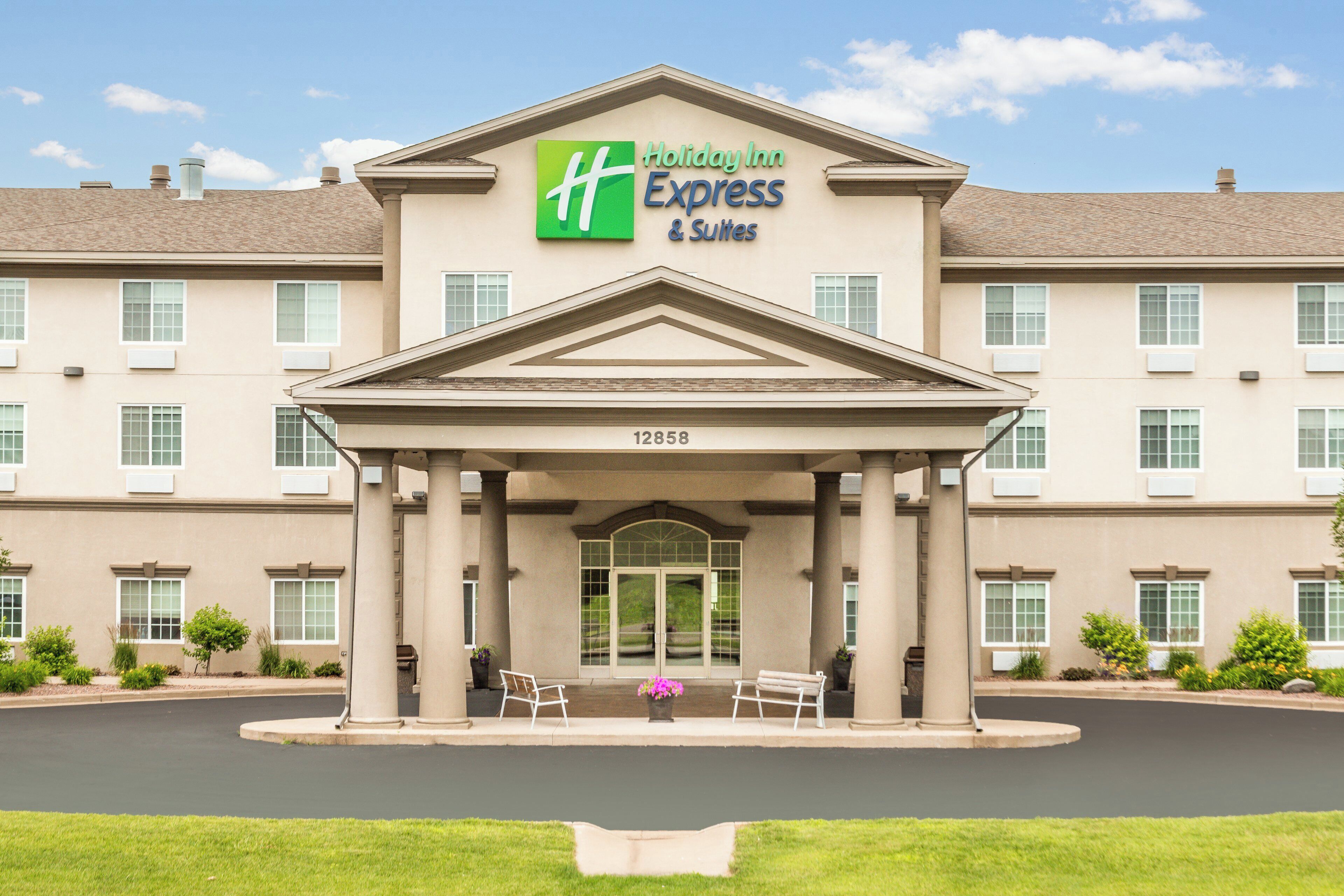 A Holiday Inn Express & Suites building with a classic architectural design, featuring a central entrance with a covered walkway and a number '12858' displayed above.