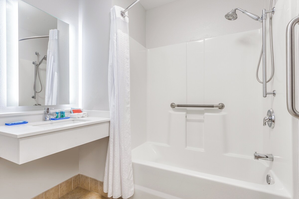 A modern bathroom with a white sink, mirror, and bathtub.