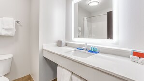 A modern bathroom with a white sink, a mirror, and a toilet.