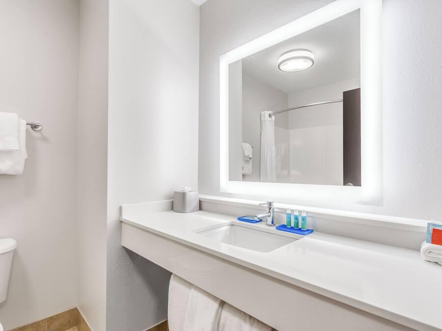 Un baño moderno con un lavamanos blanco, un espejo y un inodoro.