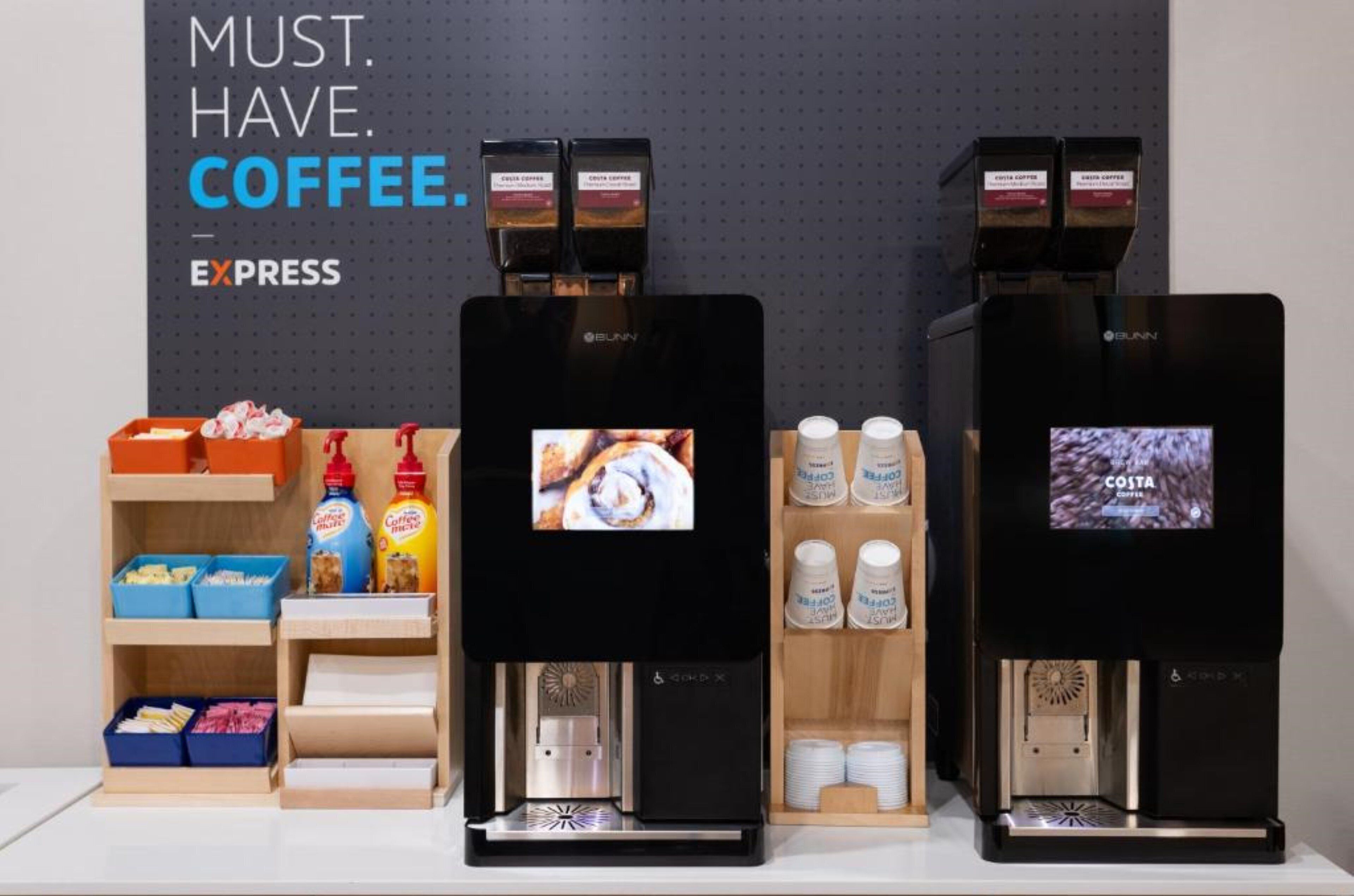 Dos máquinas de café con pantallas digitales, cápsulas de café y una repisa con artículos relacionados al café.