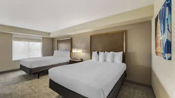 A hotel room with two beds, a nightstand with a lamp, and a large window.