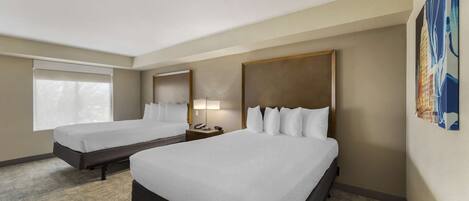 A hotel room with two beds, a nightstand with a lamp, and a large window.