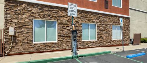 A building with a stone facade, a sign for an electric vehicle charging station, and a parking lot with marked spaces.