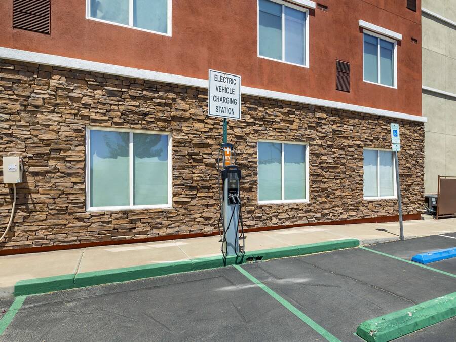 A building with a stone facade, a sign for an electric vehicle charging station, and a parking lot with marked spaces.