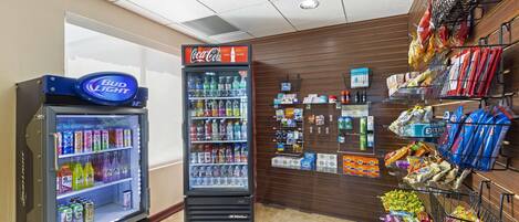 A vending machine with a Bud Light logo, a Coca-Cola refrigerator, and shelves stocked with snacks and beverages.