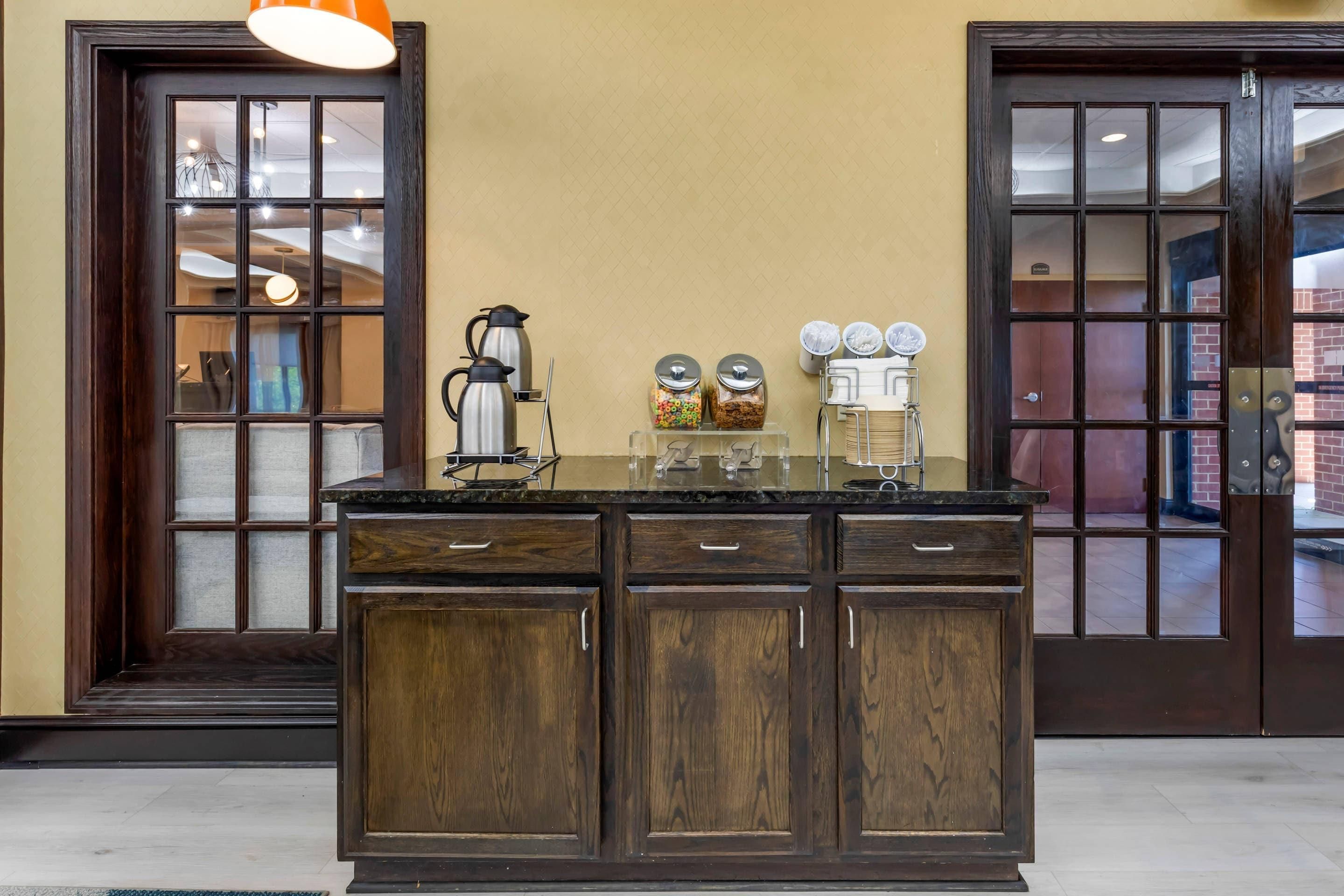 A kitchen area with a central island, two doors with glass panels, and a hanging light fixture.