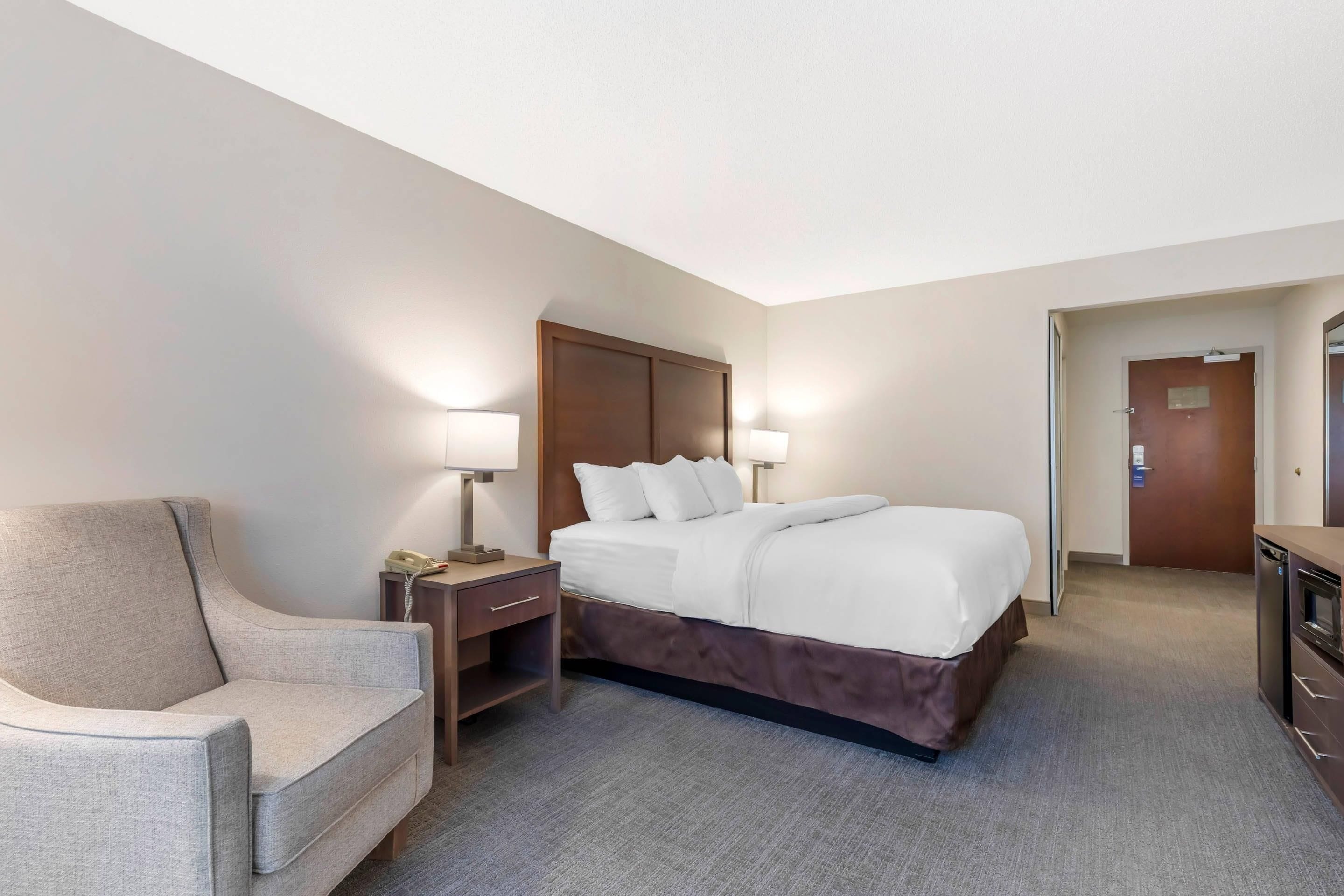 A hotel room with a bed, bedside tables, a chair, and a desk.