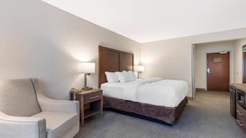 A hotel room with a bed, bedside tables, a chair, and a desk.