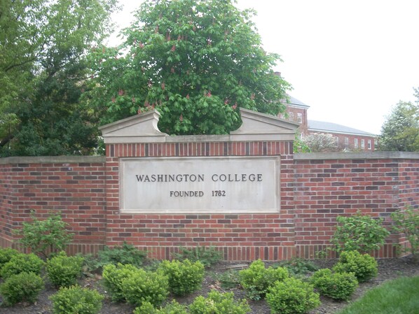 A brick wall with a sign stating "Washington College Founded 1782" and a tree above it.