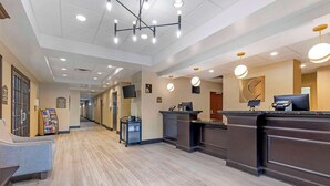 A hotel reception area with a modern design, featuring a reception desk, a seating area, and a hallway leading to other rooms. - Comfort Inn & Suites Chestertown (Chestertown)