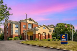 A Comfort Inn & Suites hotel with a brick facade, arched entryway, and a well-maintained lawn.